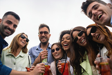 Portrait of young people having fun drinking soft drink cocktails in plastic glasses outdoor and...