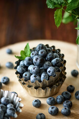 Juicy and fresh blueberries with green mint leaves on wooden table. Selective focus