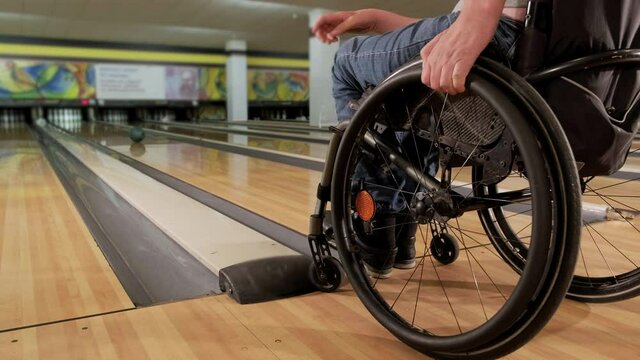 Two young disabled men in wheelchairs playing bowling in the club