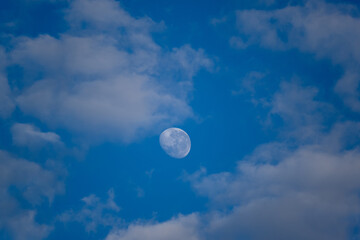 Lua entre as nuvens e céu azul da manha