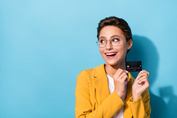 Fototapeta premium Portrait of attractive cheerful woman finance manager holding black bank card copy space isolated over bright blue color background