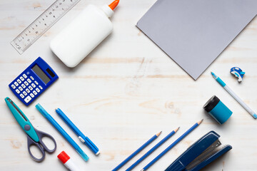 school supplies as frame on white wood background with copy space in middle