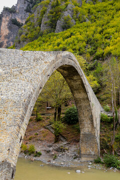 konitsa city arced bridge and voidomatis river in autumn , greece