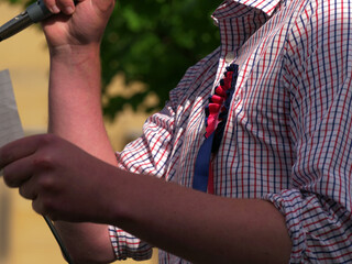 Politician wearing rosette making speech with microphone