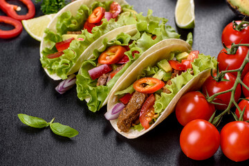 Mexican tacos with beef, tomatoes, avocado, onion and salsa sauce