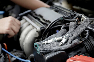 Obraz premium Cloth gloves and car spark plug on engine,Technician service and repairing service concept of car
