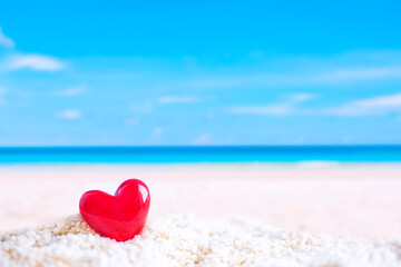 red heart shape on white sand beach 
