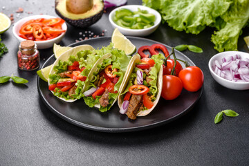 Mexican tacos with beef, tomatoes, avocado, onion and salsa sauce