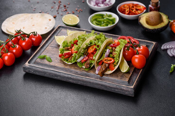 Mexican tacos with beef, tomatoes, avocado, onion and salsa sauce