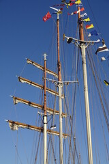 Close up view of wooden masts with many color signal flags on a clear blue sky background. Marine festival of tall ships - Sail Tallinn 2021. July, Estonia, Europe