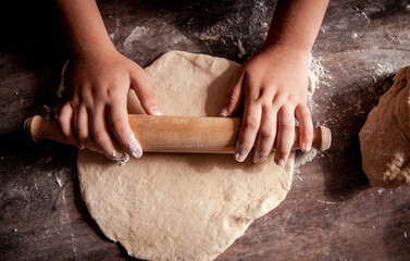 Hands roll out a tortilla from the dough
