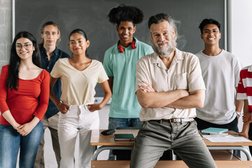 Multi-racial group of teenager secondary school students and friendly senior teacher with beard in...