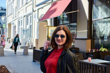 A smiling woman with brown hair is looking at camera on the street