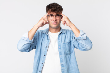 young handsome man looking concentrated and thinking hard on an idea, imagining a solution to a...
