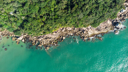 Obraz premium Aerial view of waves hitting rocks on a Brazilian beach coast. Balneario Camboriu