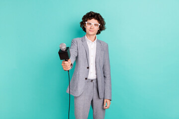 Photo of cute sweet schoolboy dressed grey suit glasses smiling holding microphone isolated teal...