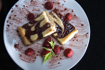 cream cheese bars  with chocolate and raspberry sauce on white plates 