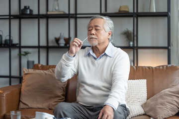 Old senior asian male hand nasal swab testing rapid tests by himself for detection of the SARS co-2 virus at home isolate quarantine concept