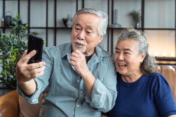 happiness asian old senior retired couple enjoy videocall to family together on sofa in living room at home,asian people use smartphone communication to family home isolation ides concept - obrazy, fototapety, plakaty