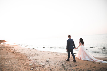 Wedding couple kissing and hugging on rocks near blue sea