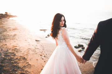 Fototapeta na wymiar Wedding couple kissing and hugging on rocks near blue sea