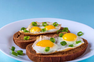 Home cooking. Whole grains Bruschettas with Fried Quail Eggs with green onions on plate