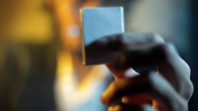 Shot of a young man playing with a matchbox in dramatic lighting. Man rotating matchbox in his hand.