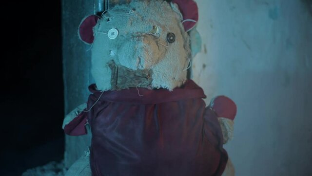 Shot of a man coming from the dark and picking up a teddy bear lyinbg on the ground and walking out of the frame in full Hd resolution and dramatic lighting.
