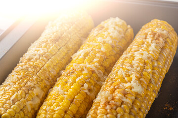 Recipe homemade cooking. Mexican Elote Corn sprinkled with cheese or parmesan, cilantro, spices and chili on baking sheet. Close up.