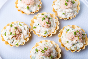 Tartlets stuffed with codfish liver, codfish caviar, cucumber and microgreens. Traditional cold portioned appetizer in a pastry basket. Close-up, top view.