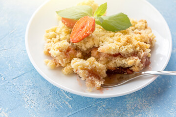 Home сooking. Rhubarb or Strawberry crumble, gluten free crisp in baking dish. Summer dessert on plate on blue background