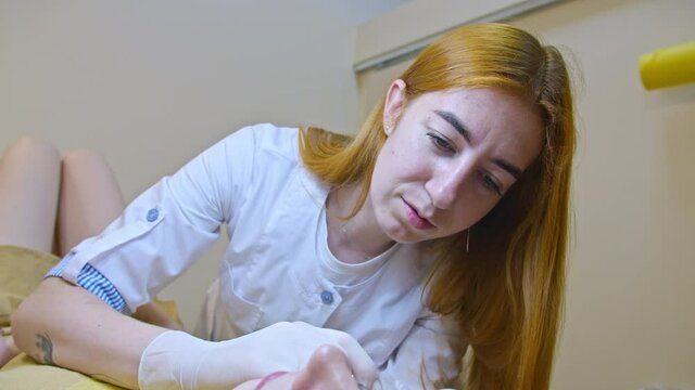 Beauty and injection concept. Cosmetology in the clinic. An experienced beautician wearing white gloves injects a subcutaneous injection with the necessary active ingredients into a woman's face for