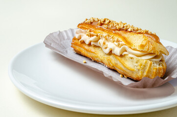 Eclair with cream and strawberries. On a white plate High quality photo