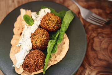 Selbstgemachte Falafel mit Fladenbrot und Salat auf Teller auf Hintergrund aus Holz mit Maserung