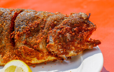 Fried and seasoned trout at a fishing festival on a white plate