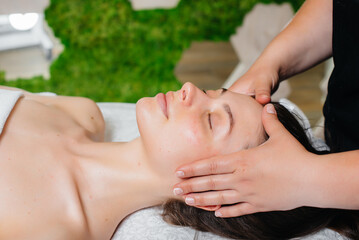 Obraz na płótnie Canvas A young pretty girl is enjoying a professional head massage at the Spa. Body care. Beauty salon