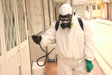 hombre con equipo de bioseguridad realizando aspersión y desinfectando