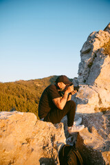 Hombre joven haciendo fotos en los alto de una montaña al atardecer