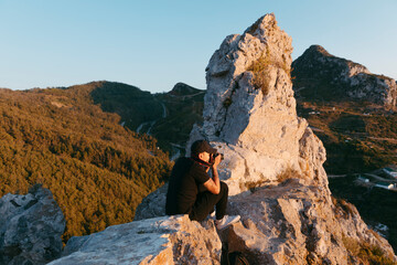 Hombre joven haciendo fotos en los alto de una montaña al atardecer
