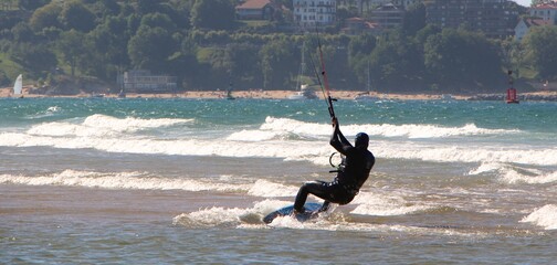 Kitesurfing or kiteboarding from the beach of Somo on a sunny windy afternoon Santander Cantabria...