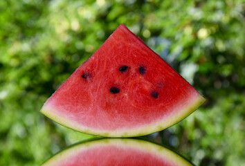 Juicy slice of red watermelon on a bright green background stock images. Piece of ripe watermelon on a fresh natural green background stock photo