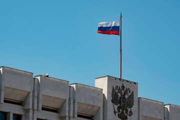 The flag and coat of arms of the Russian Federation on the administrative building. Selective focus.