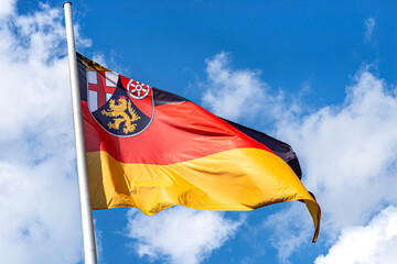 German flag on a pole waving in the wind with the coat of arms of the federal state of...