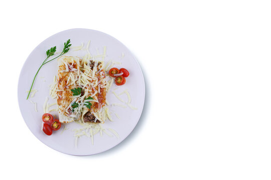 Pancakes with meat, in tomato sauce and cheese, with cilantro and grated cheese on top, and some cherry tomatoes on the plate. Top view on white background.