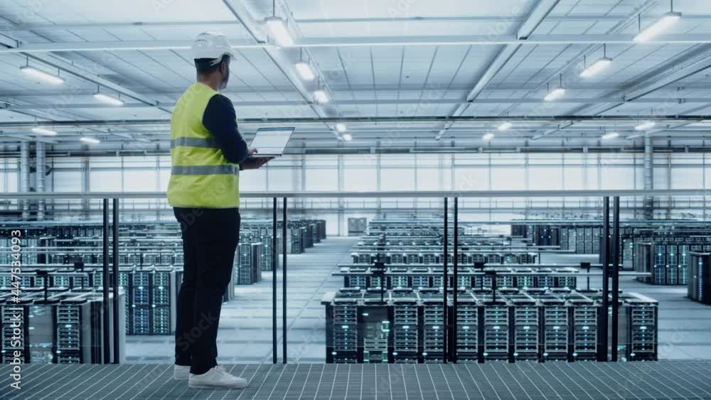 Poster Data Center Engineer in High Visibility Vest Using Laptop Computer. Server Farm Cloud Computing Facility with Black Male System Administrator Working with Data Protection Network for Cyber Security.