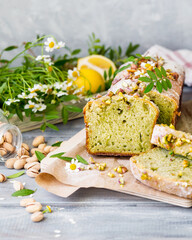 Baked green pistachio cupcake in summer. The cake is decorated with flowers in the rustic style. Lemon-flavored cupcake with chamomile flowers and pistachio leaves on top