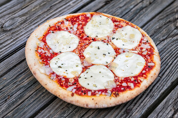 Fresh crust whole small pizza on table with melted mozzarella cheese and sprinkles and red tomato sauce closeup as Italian food cuisine