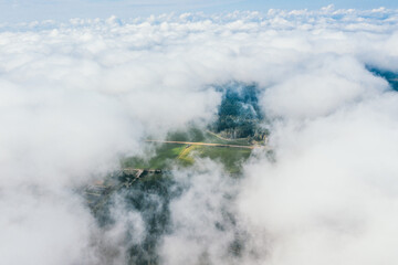 High flight in the cumulus clouds over agricultural fields in summer.