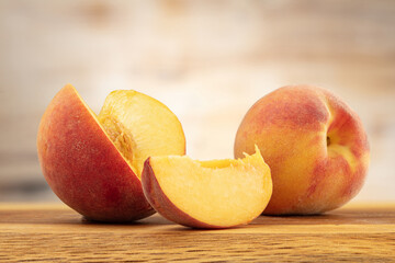 Two sliced peaches on a wooden board.