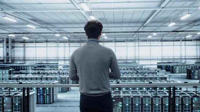 Data Center Engineer Using Laptop Computer. Server Farm Cloud Computing Specialist Facility with Adult Male System Administrator Working with Data Protection Network for Cyber Security.